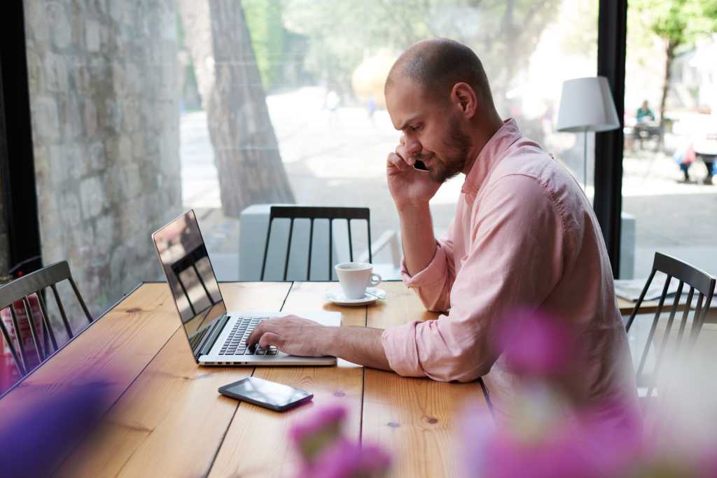 Man using Mac laptop and talking on phone